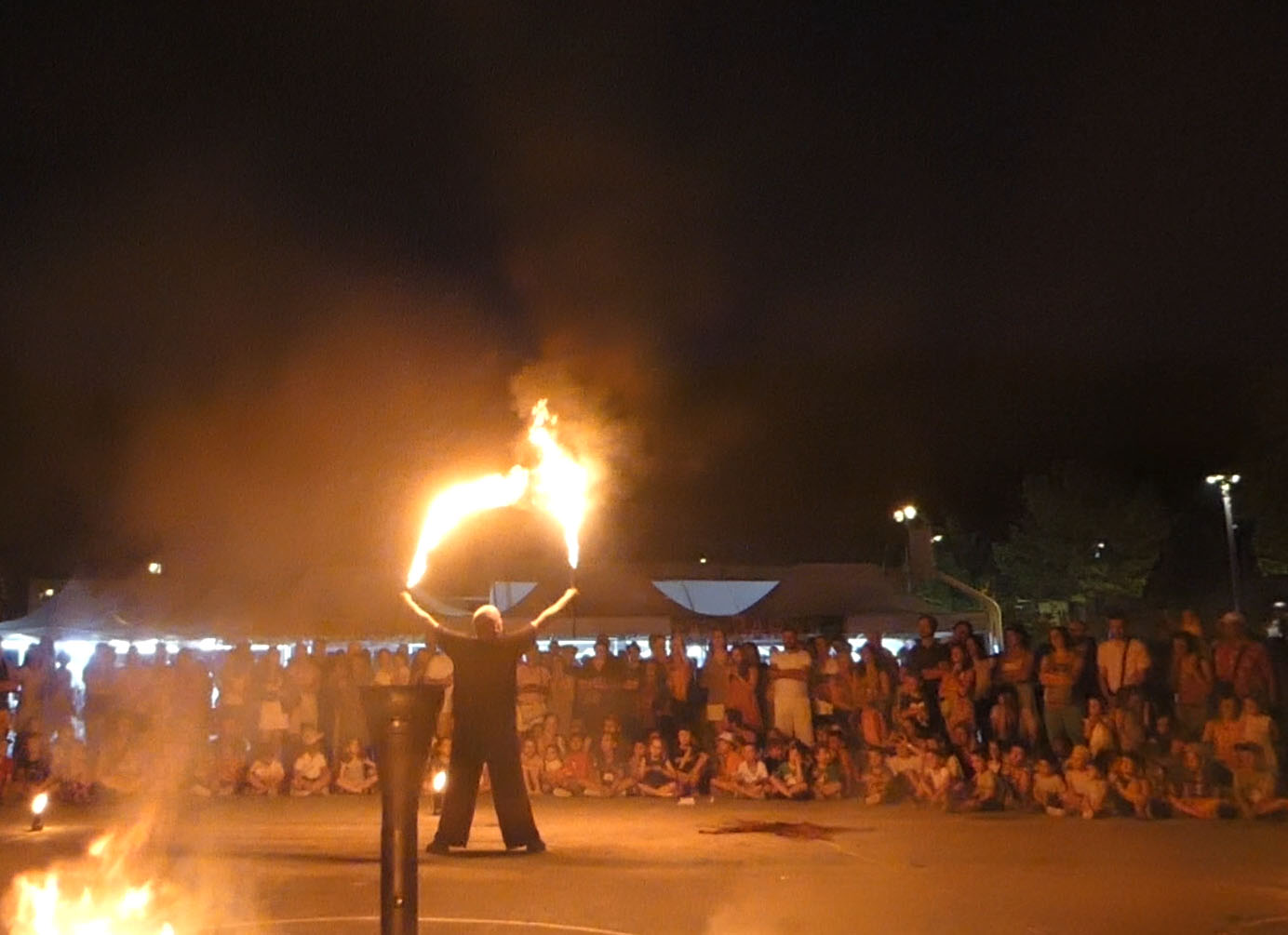 Artiste tenant deux torches enflammées devant le public